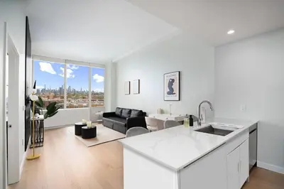 a white kitchen and living room with a couch at Exclusive 1BR Apt with NYC View in Hoboken