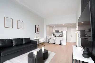 a living room with a black couch and a kitchen at Exclusive 1BR Apt with NYC View in Hoboken