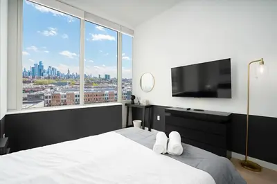a bedroom with a large white bed and a large window at Exclusive 1BR Apt with NYC View in Hoboken