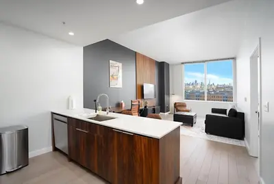 a kitchen with a sink and a living room at Exclusive 1BR Apt with NYC View in Hoboken