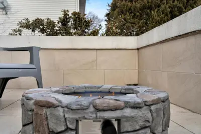 a stone fire pit in a yard with a chair at Fire and Fun Luxe Stay w Pool Hot Tub and Game Room in Linden