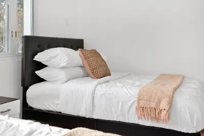 a bed with white sheets and a black headboard with pillows at Fire and Fun Luxe Stay w Pool Hot Tub and Game Room in Linden
