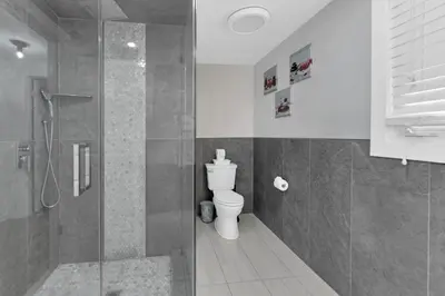 a bathroom with a toilet and a glass shower at Fire and Fun Luxe Stay w Pool Hot Tub and Game Room in Linden