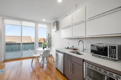 a kitchen with white cabinets and a large window at Designer Studio Loft - Balcony Pool Gym in Philadelphia