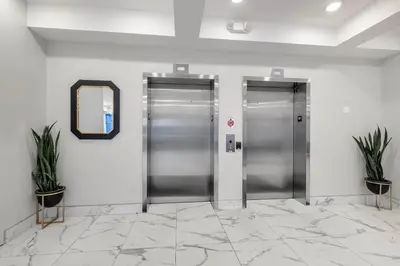 two silver elevators in a lobby with two plants at Designer Studio Loft - Balcony Pool Gym in Philadelphia