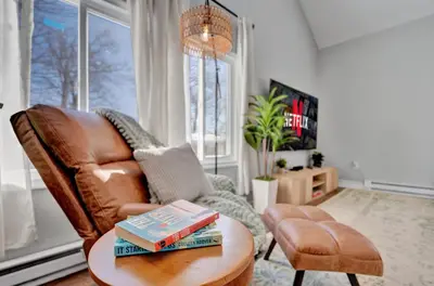 a living room with a leather chair with books on a table at Palomino Ranch namaste-sunroom, hot tub, game room, king beds, fire pit, BBQ, pet-friendly in Tobyhanna