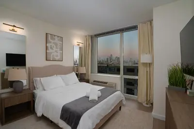 a bedroom with a large bed and a large window at Ultra Luxury Apt - Panoramic NYC View - Minutes to City in Hoboken