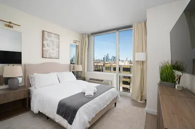 a bedroom with a large bed and a large window at Ultra Luxury Apt - Panoramic NYC View - Minutes to City in Hoboken