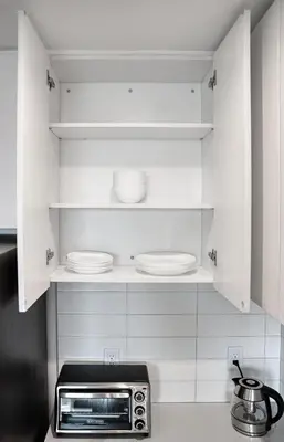 a kitchen with white cabinets with plates and a microwave at Ultra Luxury Apt - Panoramic NYC View - Minutes to City in Hoboken