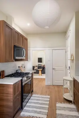 a kitchen with wooden cabinets and a stove top oven at Bright & Modern - 35 Mins to NYC - Extended Stays in Jersey City