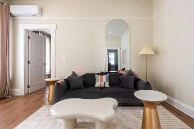 a living room with a black couch and a mirror at Bright & Modern - 35 Mins to NYC - Extended Stays in Jersey City