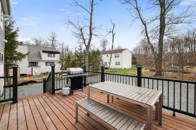 a wooden deck with a bench and a grill at Spacious 5BR Home In Heart Of Poconos By Camelback Skiing Swimming Lake in Tobyhanna