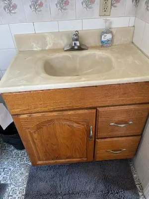 a sink in a bathroom with a wooden cabinet at Amazing three bedrooms Apartment near EWR and NYC in Linden