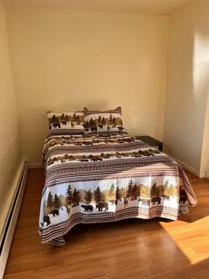 a bed with a blanket on it in a room at Amazing three bedrooms Apartment near EWR and NYC in Linden