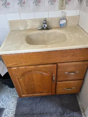 a sink in a bathroom with a wooden cabinet at Amazing three bedrooms Apartment near EWR and NYC in Linden