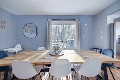 a dining room with a wooden table and white chairs at Charming Lakeside Retreat for 10 in Tobyhanna