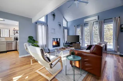 a living room with a brown leather couch and white chairs at Charming Lakeside Retreat for 10 in Tobyhanna
