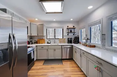 a kitchen with white cabinets and a stainless steel refrigerator at Charming Lakeside Retreat for 10 in Tobyhanna
