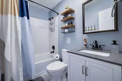 a bathroom with a toilet and a sink and a mirror at Charming Lakeside Retreat for 10 in Tobyhanna