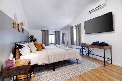 a bedroom with a bed and a desk and a flat screen tv at Charming Lakeside Retreat for 10 in Tobyhanna