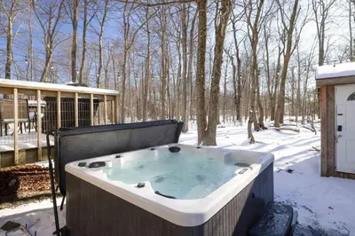 a jacuzzi tub in the snow in a yard at Charming Lakeside Retreat for 10 in Tobyhanna