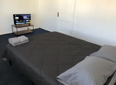 a bedroom with a large bed and a television at Private house with 3 bedrooms and 1 bathroom, free parking, convenient to NYC Manhattan bus and train, MetLife Stadium FIFA World Cup 35 minutes away in Perth Amboy