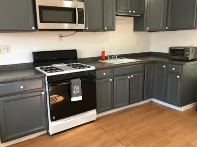 a kitchen with gray cabinets and a stove and microwave at Private house with 3 bedrooms and 1 bathroom, free parking, convenient to NYC Manhattan bus and train, MetLife Stadium FIFA World Cup 35 minutes away in Perth Amboy