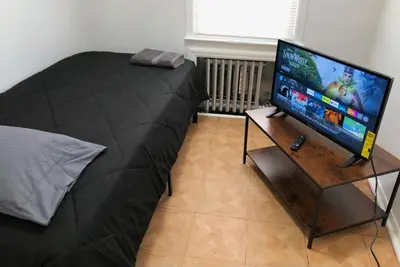 a bedroom with a bed and a flat screen tv at Private house with 3 bedrooms and 1 bathroom, free parking, convenient to NYC Manhattan bus and train, MetLife Stadium FIFA World Cup 35 minutes away in Perth Amboy