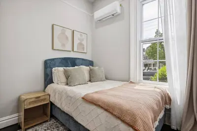 a bedroom with a bed with a blue headboard and a window at Chic & Modern - 30 Mins to NYC in Jersey City
