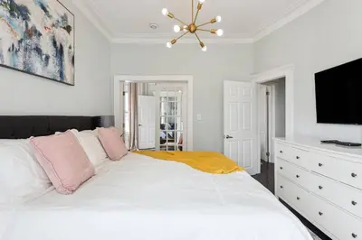 a bedroom with a large white bed and a flat screen tv at Chic & Modern - 35 Mins to NYC - Extended Stays in Jersey City