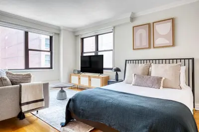 a bedroom with a bed and a tv and a couch at Murray Hill Studio w Gym Doorman nr 6 train NYC-628 in New York