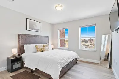 a bedroom with a large bed and two windows at Downtown NWK 1BR- Free Parking Easy NYC Access in Newark