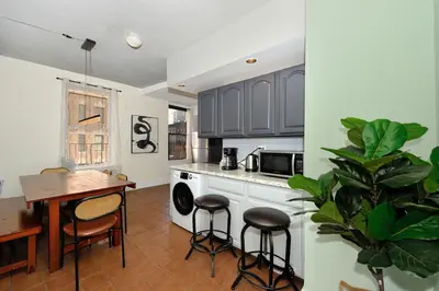 a kitchen with black cabinets and a table and stools at 5 Bedroom 2 Bath Full Floor Midtown in New York