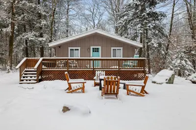 a cabin in the snow with a table and chairs at Family Friendly Cabin With A Firepit And A Hot Tub In Heart of Poconos in Pocono Pines