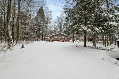 a snow covered yard with a house in the background at Family Friendly Cabin With A Firepit And A Hot Tub In Heart of Poconos in Pocono Pines
