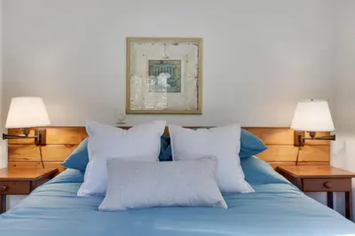 a bed with blue sheets and pillows with two lamps at Family Friendly Cabin With A Firepit And A Hot Tub In Heart of Poconos in Pocono Pines