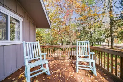 two chairs sitting on the porch of a house at Family Friendly Cabin With A Firepit And A Hot Tub In Heart of Poconos in Pocono Pines