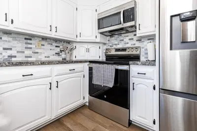 a kitchen with white cabinets and a black oven at Serenity Inn in Ronks