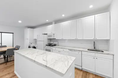 a kitchen with white cabinets and a marble counter top at 105- 4BRs in the Heart of the East Village in New York