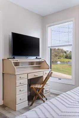 a bedroom with a desk with a tv and a window at New House within Campground in Mifflinburg