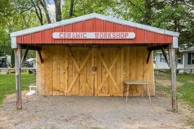 a barn with a sign on it with a bench in front at New House within Campground in Mifflinburg