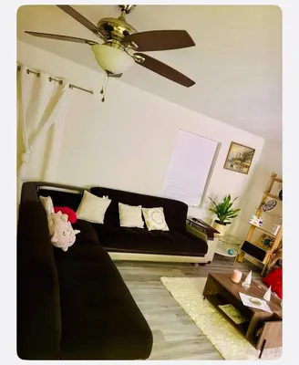 a living room with a black couch and a ceiling fan at Warmth Private Room in Stillwater Lake Estates