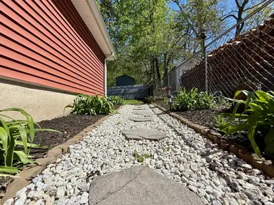 a backyard with a rock walkway next to a house at Peak to Lake Escape in Greenwood Lake
