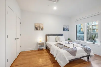 a white bedroom with a large bed and a window at Chic 1BR Retreat - Pool, Gym Balcony Views in Philadelphia