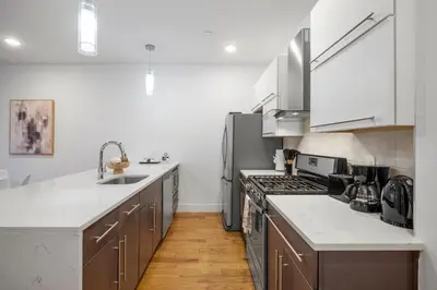 a kitchen with stainless steel appliances and wooden floors at Chic 1BR Retreat - Pool, Gym Balcony Views in Philadelphia