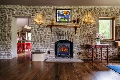 a living room with a stone wall with a fireplace at Antrim Streamside in Livingston Manor