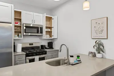 a kitchen with a sink and a stainless steel refrigerator at Free Parking 1BR Spacious BoHo 30Min to NYC in Bayonne