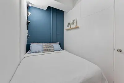 a small bedroom with a white bed with a blue wall at 4 Bedroom 1 Bathroom Hudson Yard in New York
