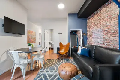 a living room with a black leather couch and a brick wall at 4 Bedroom 1 Bathroom Hudson Yard in New York