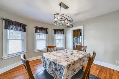 a dining room with a table and chairs and windows at 1 Mi to Dtwn Binghamton Apt with Covered Balcony! in Binghamton